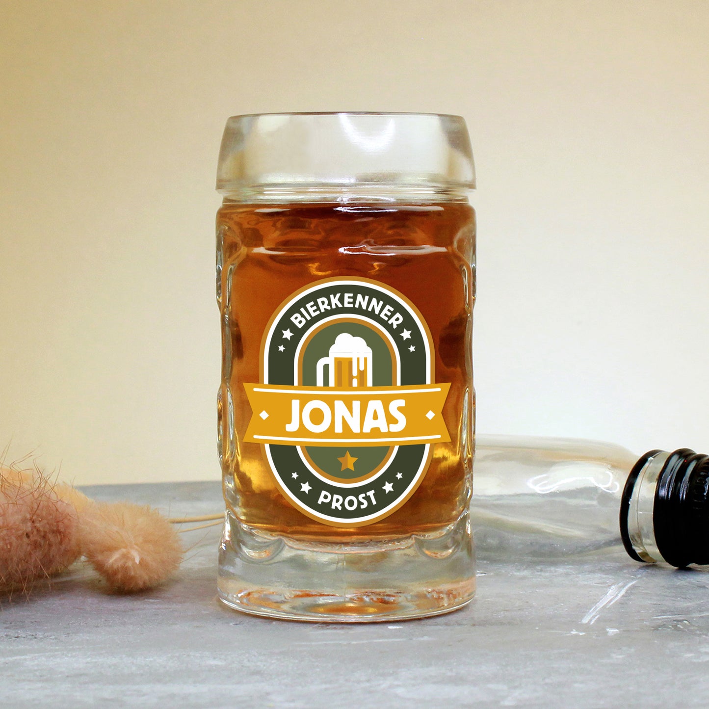 Mini-Bierkrug mit Henkel und 4 cl Inhalt, rechts im Bild eine kleine Likörflasche, vorn der Namensaufdruck „Jonas“ im Bierkenner-Design – eignet sich perfekt als Gag-Geschenk oder Ergänzung zu Männerpräsenten