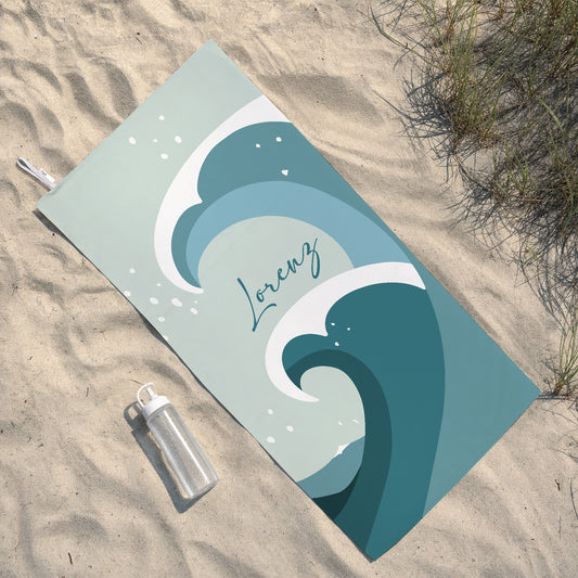 Personalisiertes Sporthandtuch mit blauem Wellenmotiv und Name Lorenz liegt im Sand neben Trinkflasche