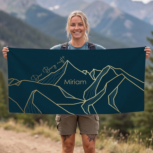 Person hält personalisiertes Sporthandtuch mit Bergmotiv und Name Miriam vor Bergkulisse