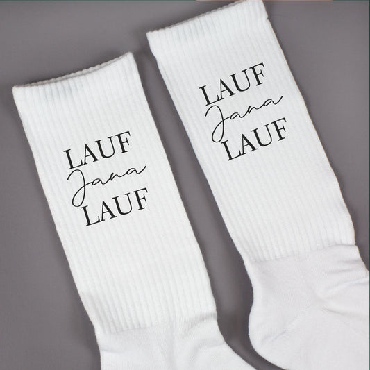 Nahaufnahme von weißen Socken mit „Lauf Jana Lauf“-Aufdruck und gerippter Struktur