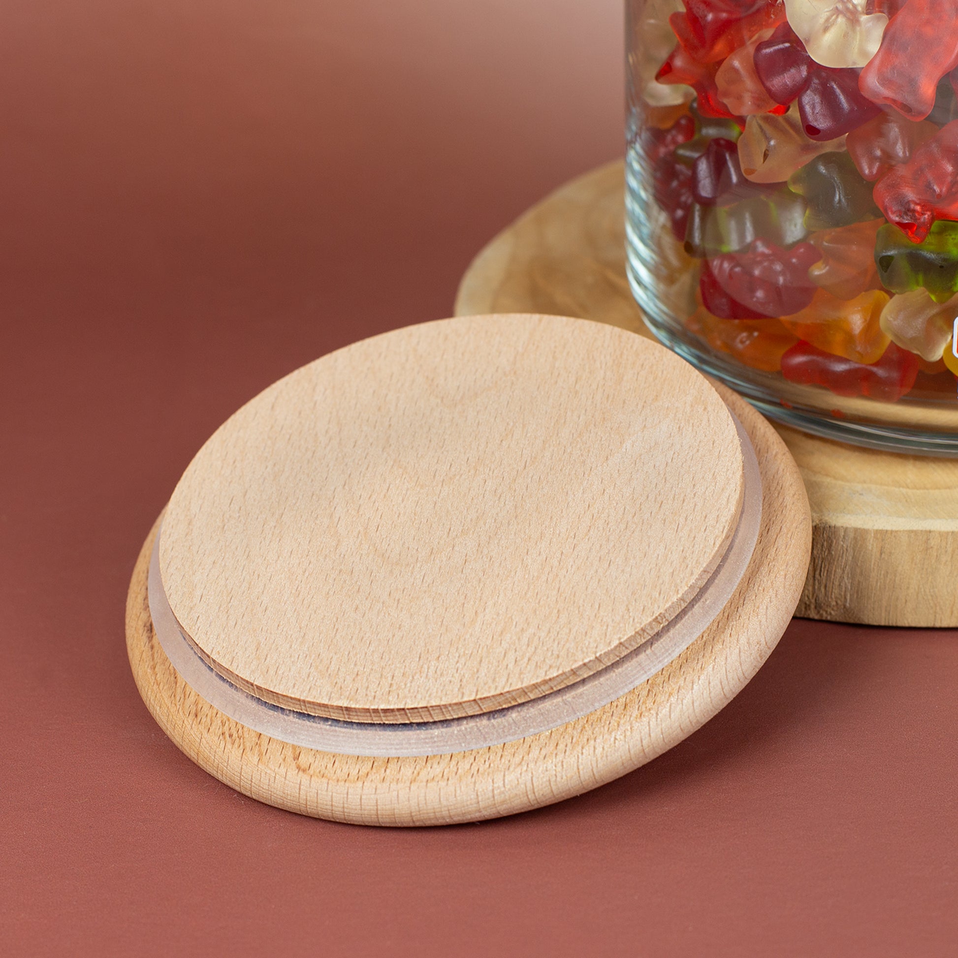 Nahaufnahme vom Holzdeckel mit Silikondichtring neben einem HARIBO Vorratsglas mit bunten Süßigkeiten
