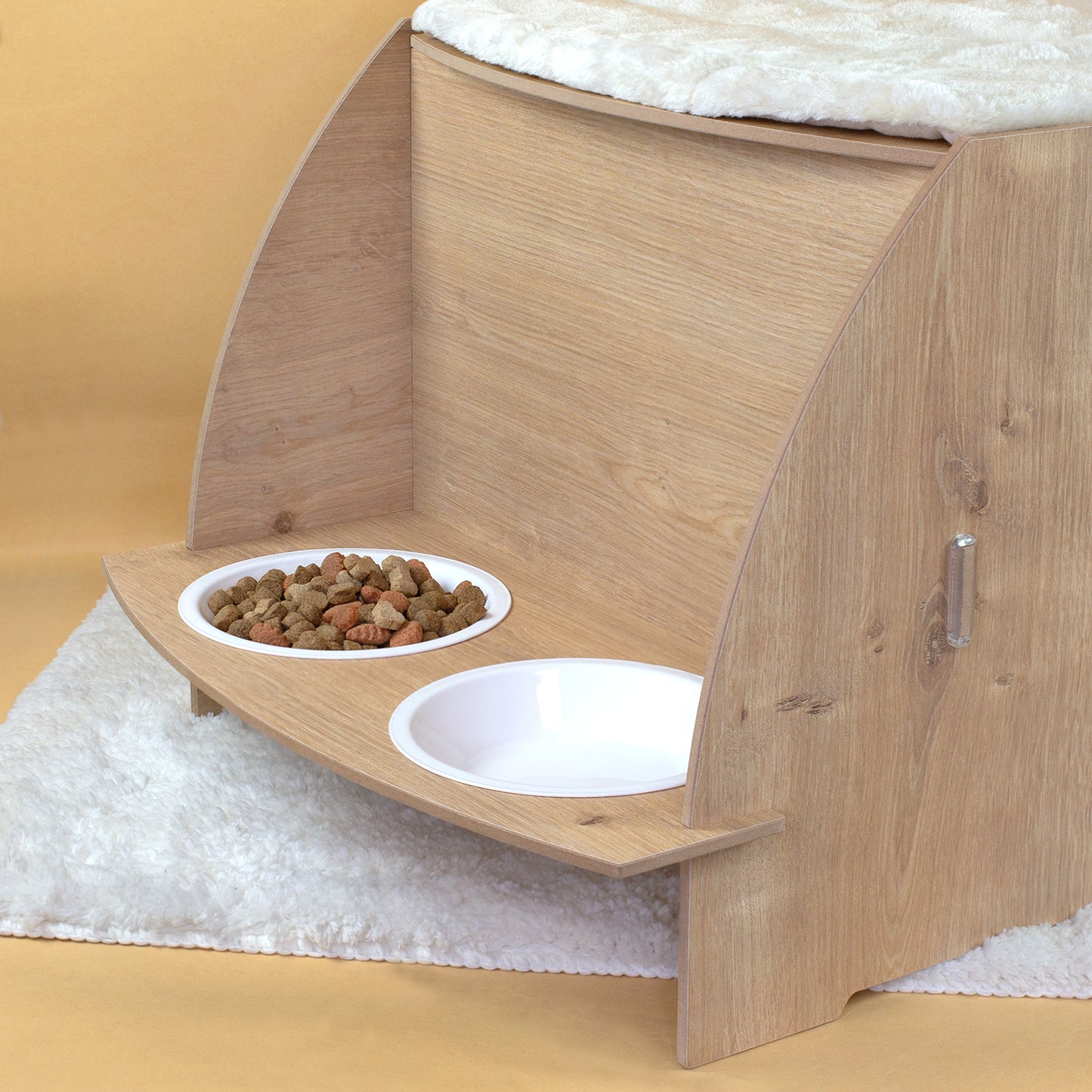 Detailansicht der Futterstation am Katzenhaus in Eiche-Optik mit zwei weißen Näpfen, einer mit Trockenfutter gefüllt