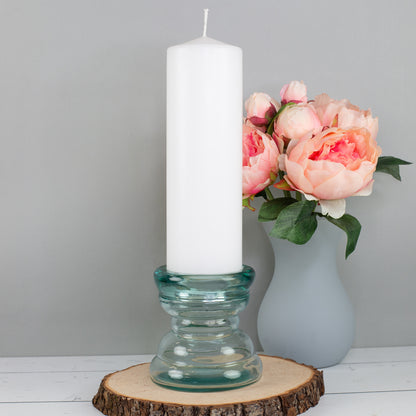 Recycelter Glas Kerzenständer mit weißer Stumpenkerze und rosa Blumen im Hintergrund