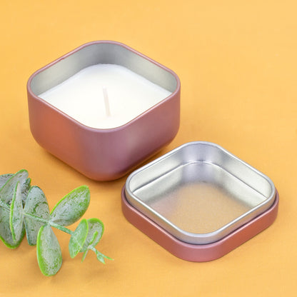 Geöffnete roségoldene Mini-Duftkerze mit Metalldeckel und weißem Wachs neben Eukalyptus