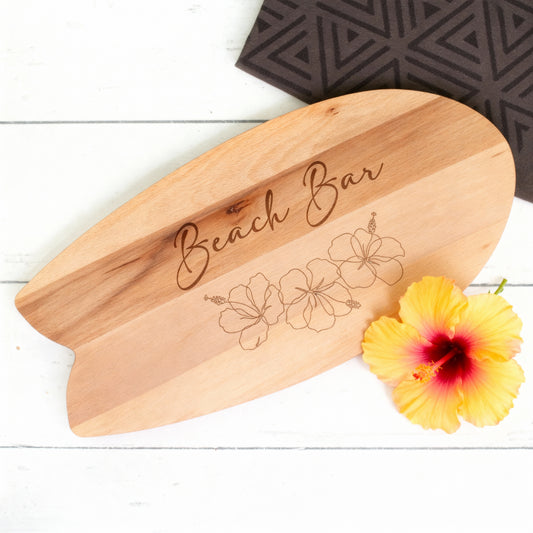 Surfbrett-Servierbrett aus Holz mit Hibiskusgravur und gelber Blüte als sommerliche Dekoration