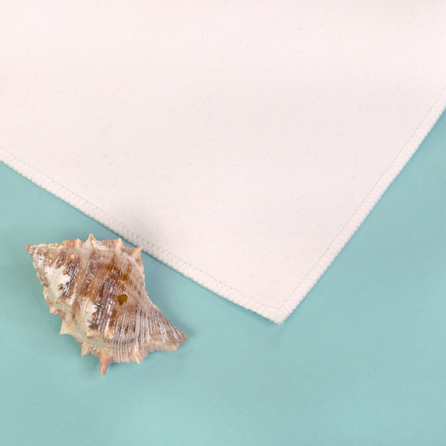 Nahaufnahme der gesäumten Ecke eines weißen Sporthandtuchs auf blauem Hintergrund