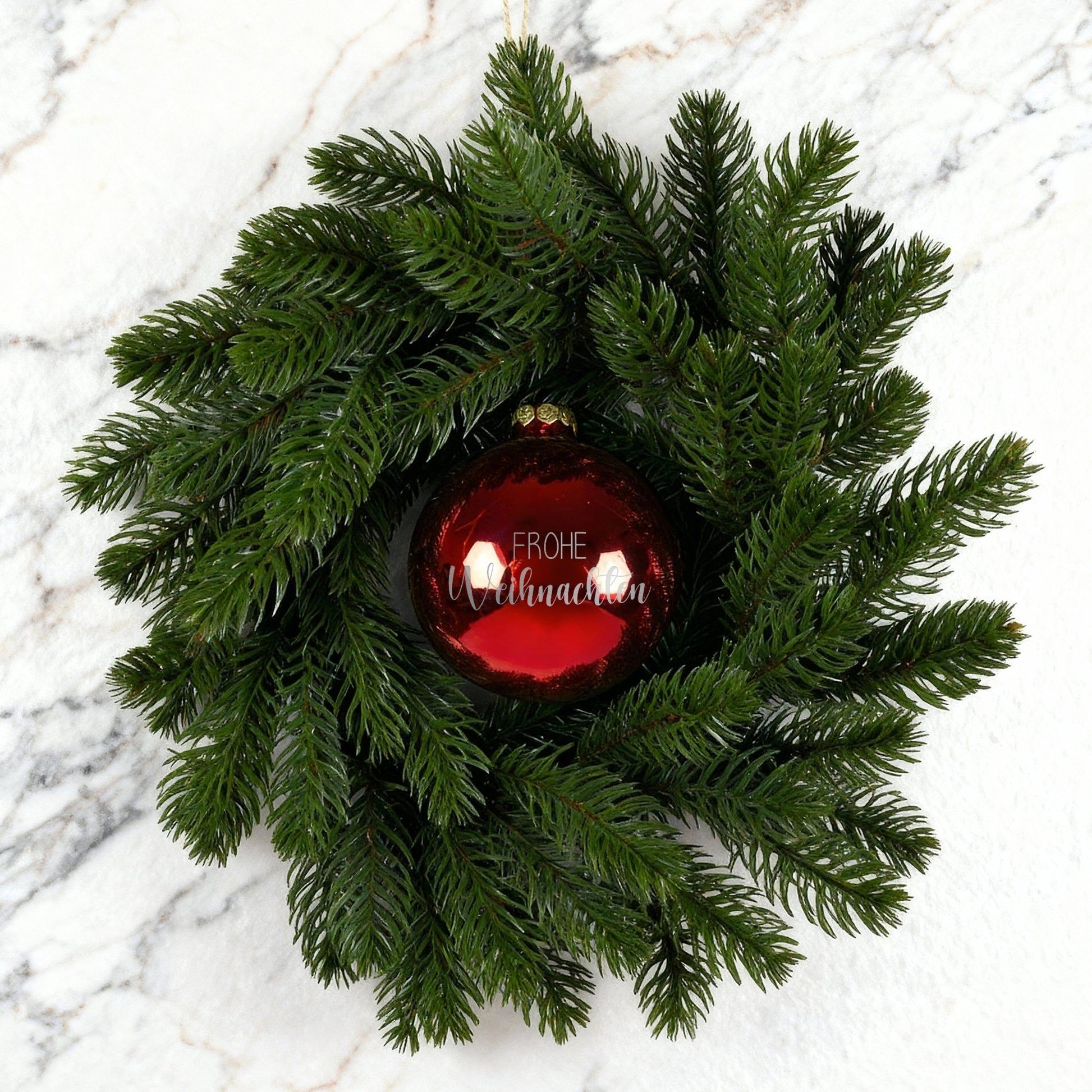 Weihnachtskranz mit roter Kugel Frohe Weihnachten auf weiß-marmoriertem Hintergrund
