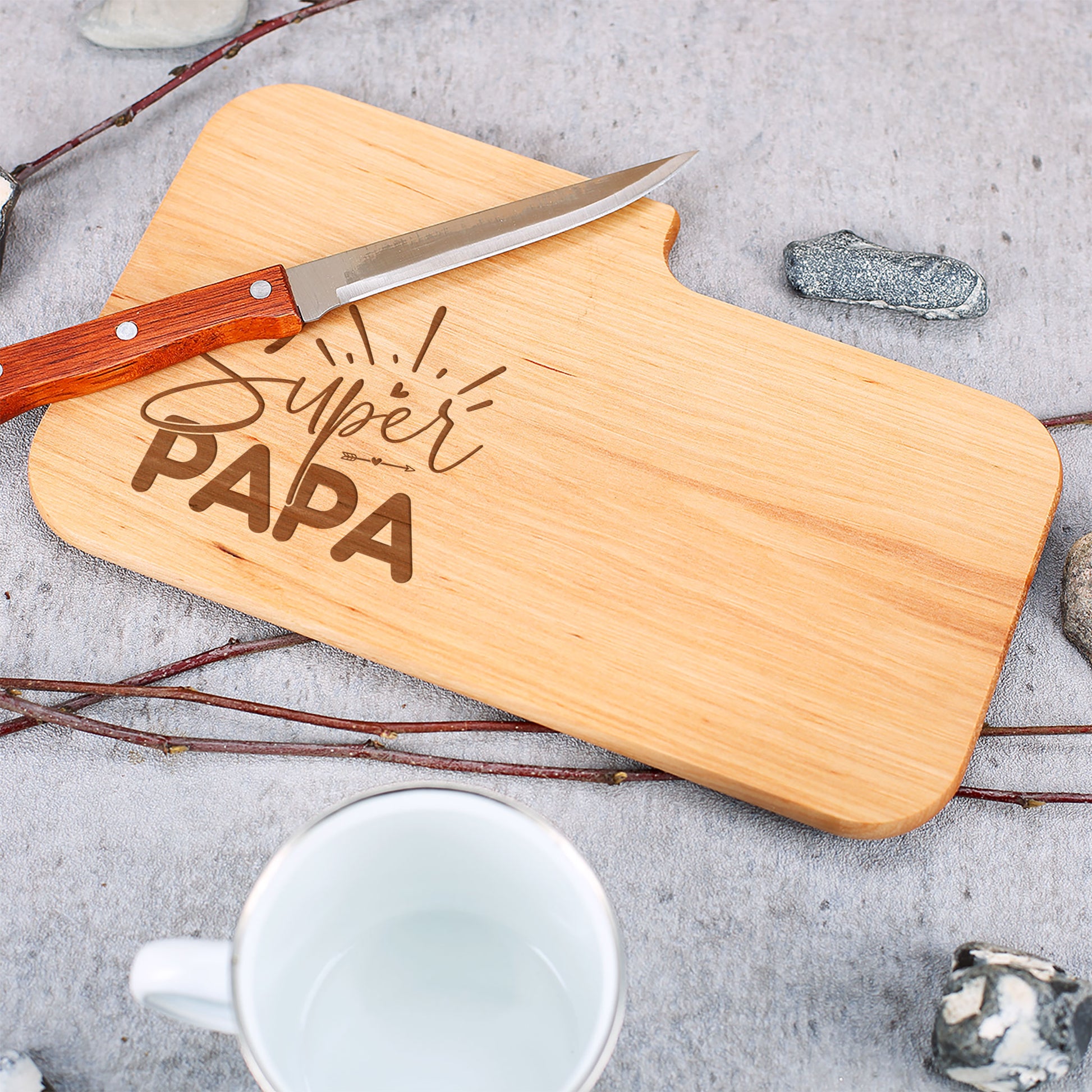 Detailaufnahme von Holzbrett mit Gravur Super Papa und Messer