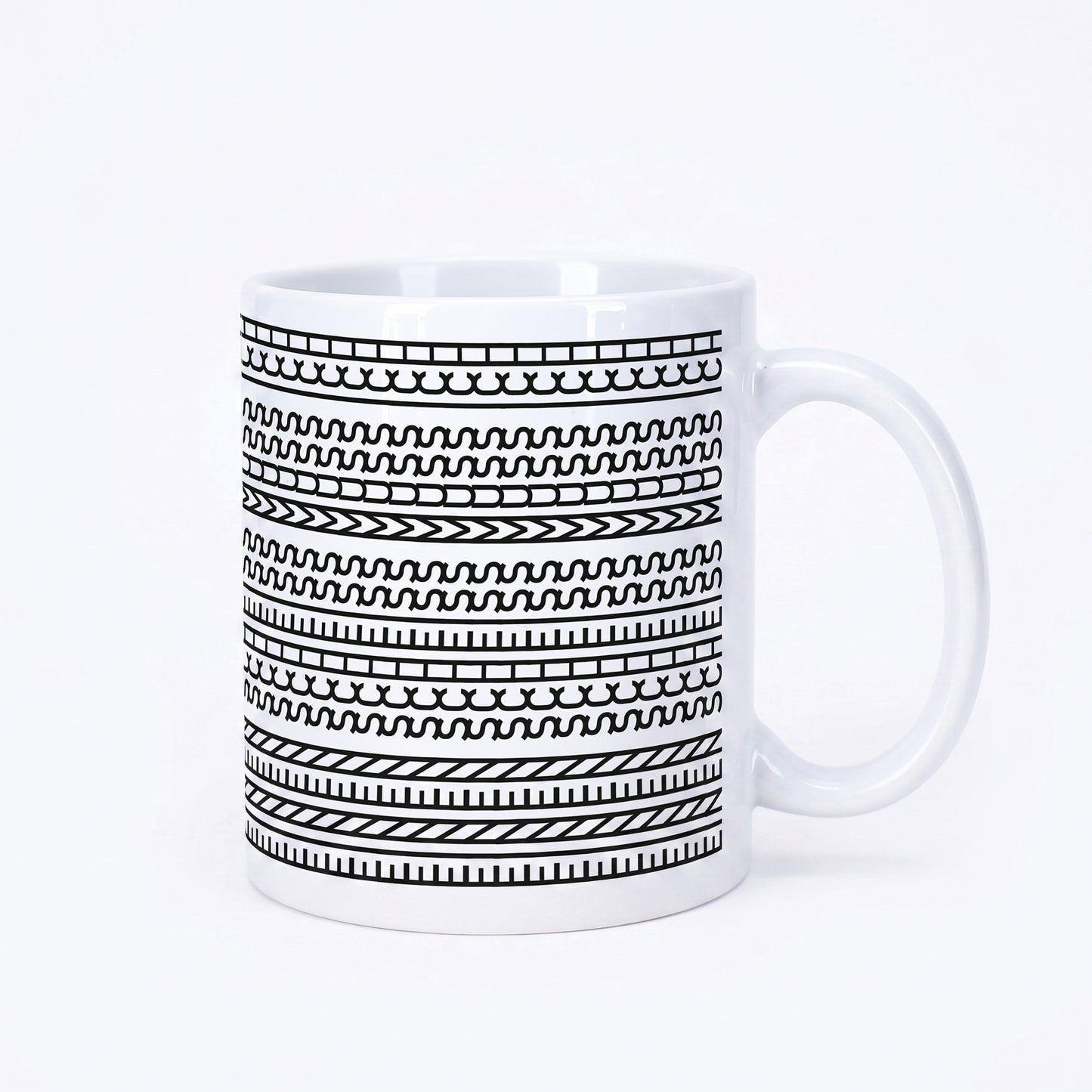 Weiße Kaffeetasse mit schwarzem grafischem Muster und versteckter Botschaft „Einen Scheiss muss ich“