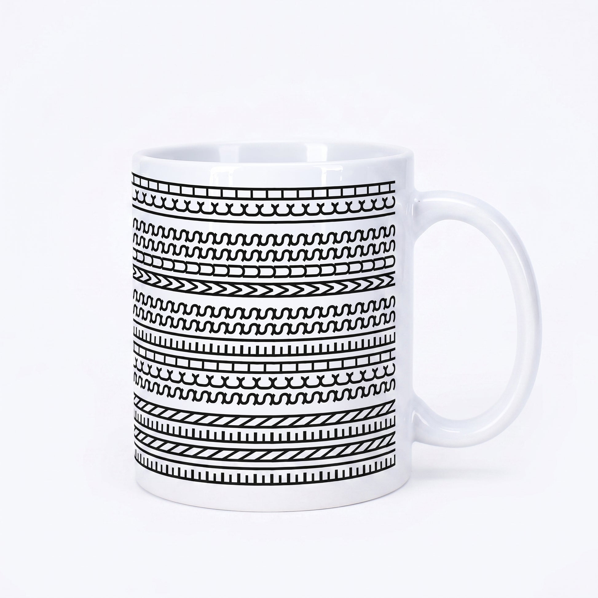 Weiße Kaffeetasse mit schwarzem grafischem Muster und versteckter Botschaft „Einen Scheiss muss ich“