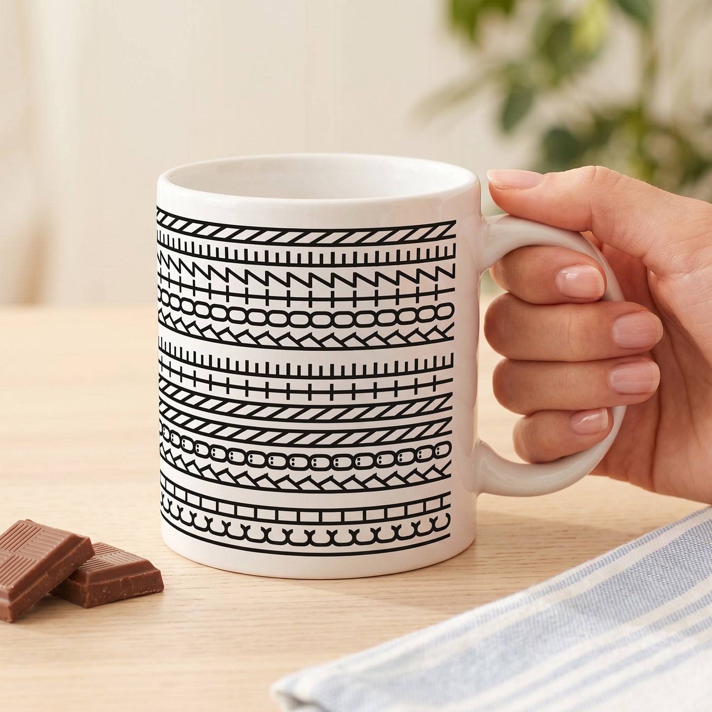 Weiße Kaffeetasse mit schwarzem Muster und versteckter Botschaft „Ich könnte kotzen“ in der Hand