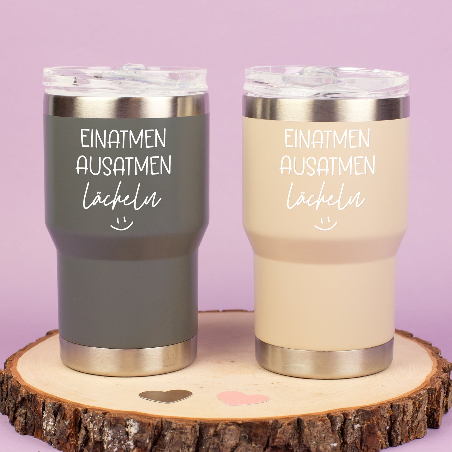 Zwei Thermobecher in Grau und Beige mit Spruch Einatmen Ausatmen Lächeln auf Holzscheibe dekoriert