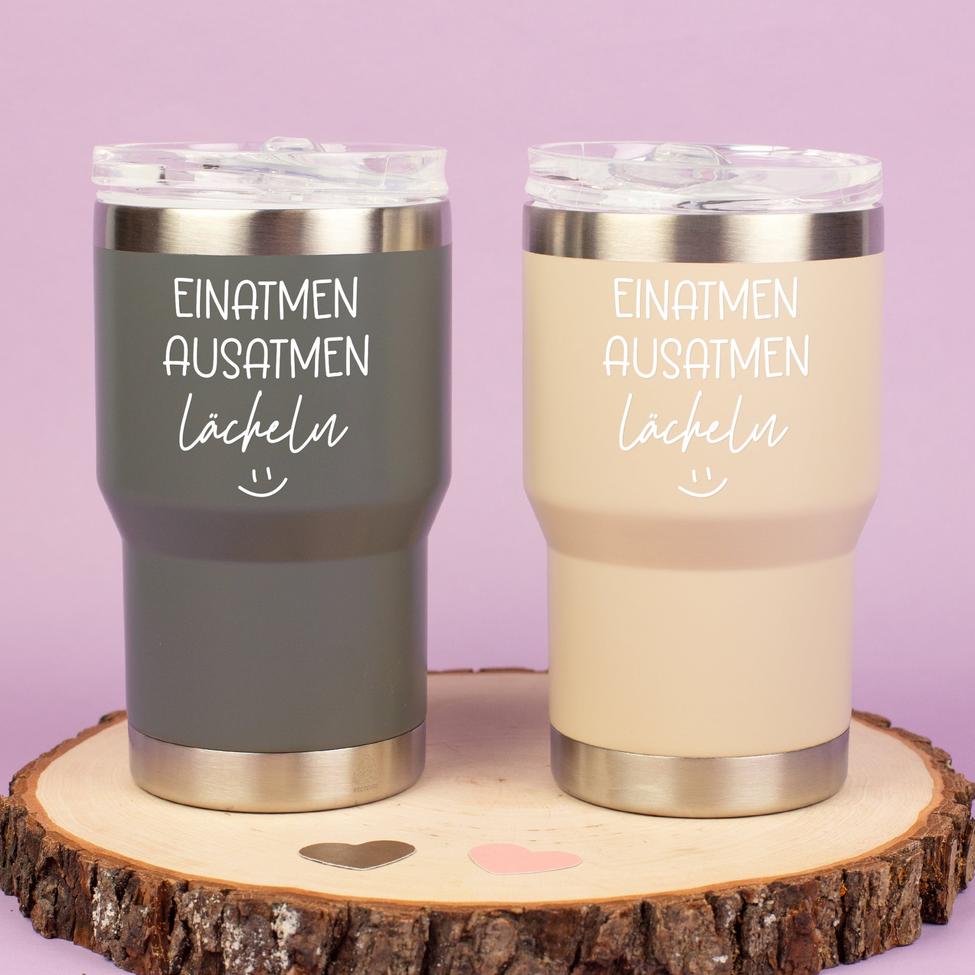 Zwei Thermobecher in Grau und Beige mit Spruch Einatmen Ausatmen Lächeln auf Holzscheibe dekoriert