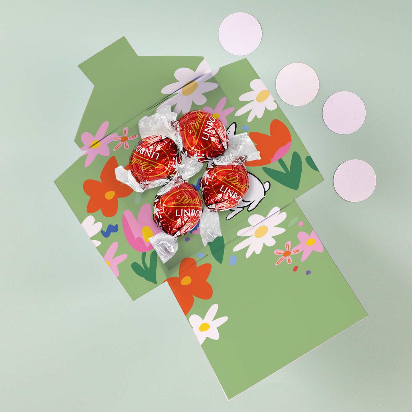 Osterbox mit Lindt Lindor Kugeln und Blumenmotiv auf grünem Hintergrund
