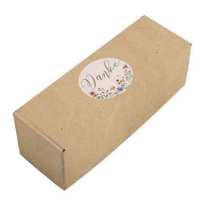 Freigestellte Geschenkverpackung im natürlichen Kraftpapier-Look mit floralem Kreisdesign und dem Wort Danke