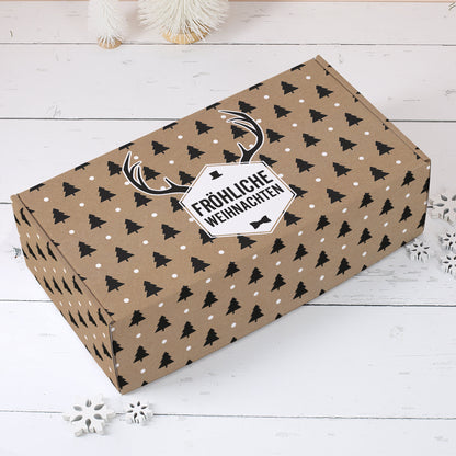 Braune Geschenkbox zu Weihnachten mit schwarzen Tannen, weißen Punkten, Rentiergeweih und Fröhliche Weihnachten Etikett