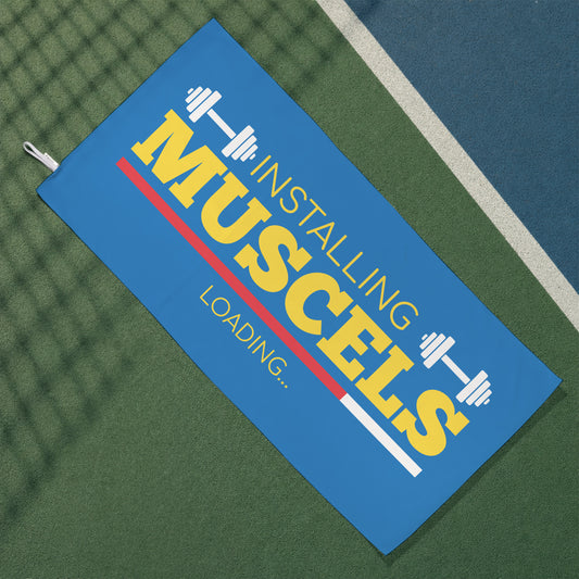 Blaues Gym Handtuch mit Hantelmotiv und Installing Muscles Loading Schriftzug auf Sportplatz