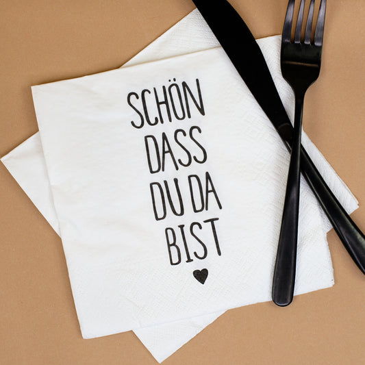 Weiße Motivserviette „Schön dass du da bist“ mit schwarzem Besteck als Tischdekoration