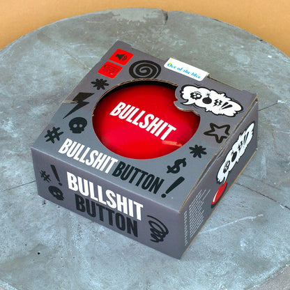 Bullshit Button in Verpackung auf runder Betonplatte