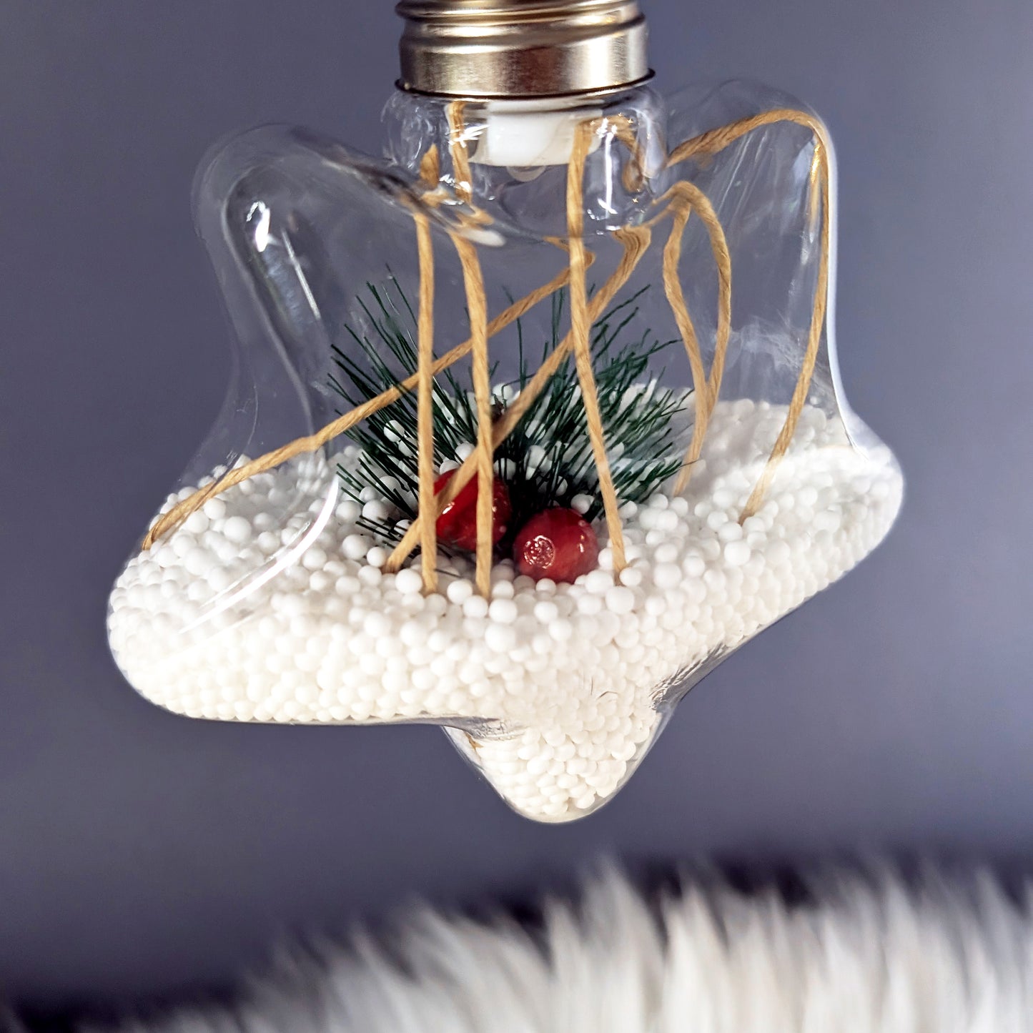 Sternförmige LED-Weihnachtskugel mit Tannenzweig, roten Beeren und warmem Licht.