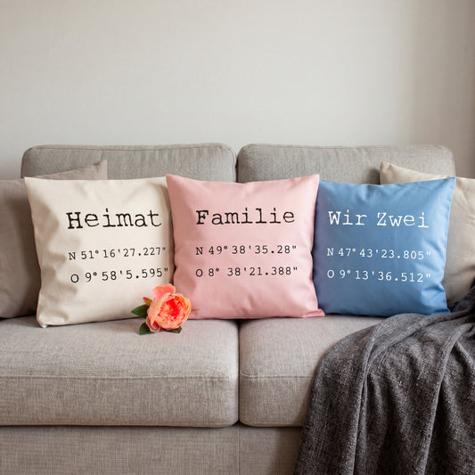 Personalisierte Koordinaten Kissen in Natur, Rosa und Blau mit Wunschtext auf Sofa