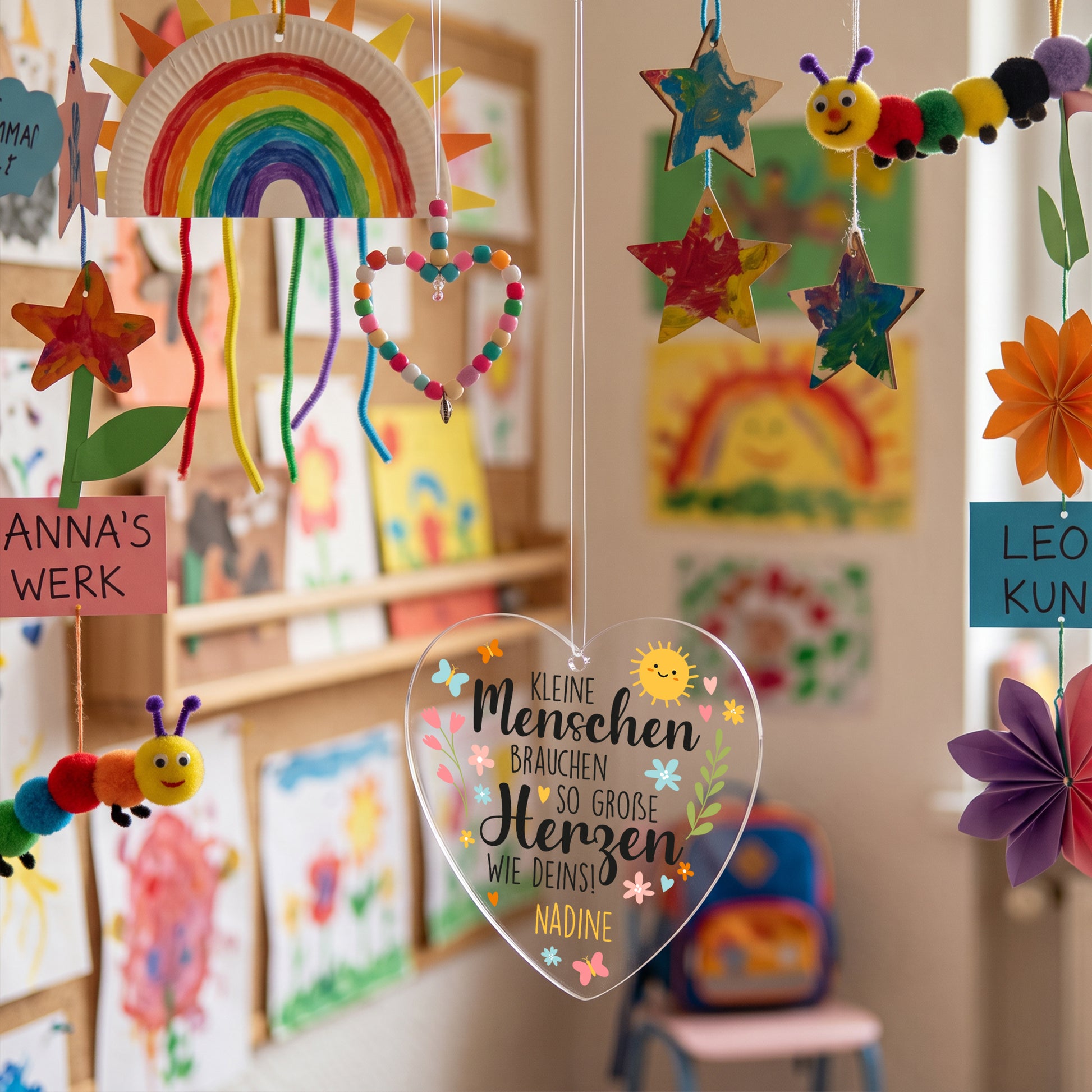 Personalisiertes Acrylherz mit Spruch für Erzieher im bunt dekorierten Kindergartenraum aufgehängt