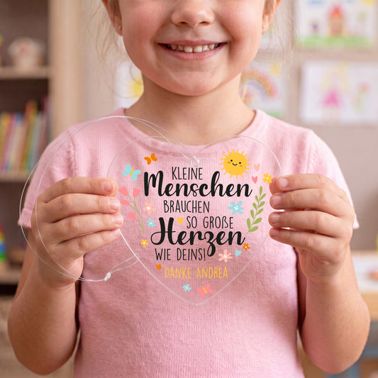 Kind hält transparentes Acrylherz mit Spruch für Erzieher und personalisiertem Text Danke Andrea