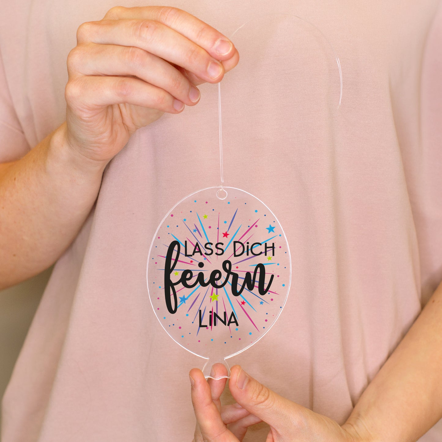 Personalisierter Acrylanhänger in Luftballonform mit Aufdruck Lass dich feiern und Name Lina in den Händen gehalten