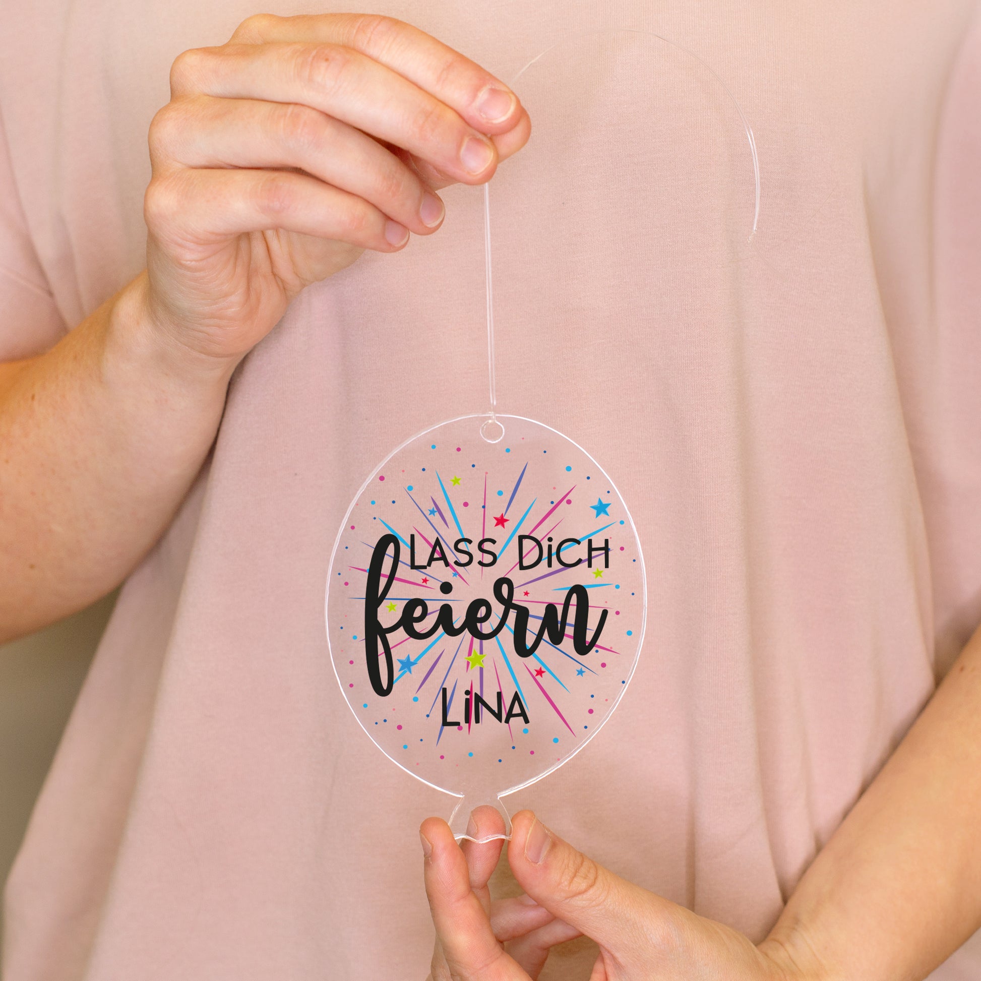 Personalisierter Acrylanhänger in Luftballonform mit Aufdruck Lass dich feiern und Name Lina in den Händen gehalten