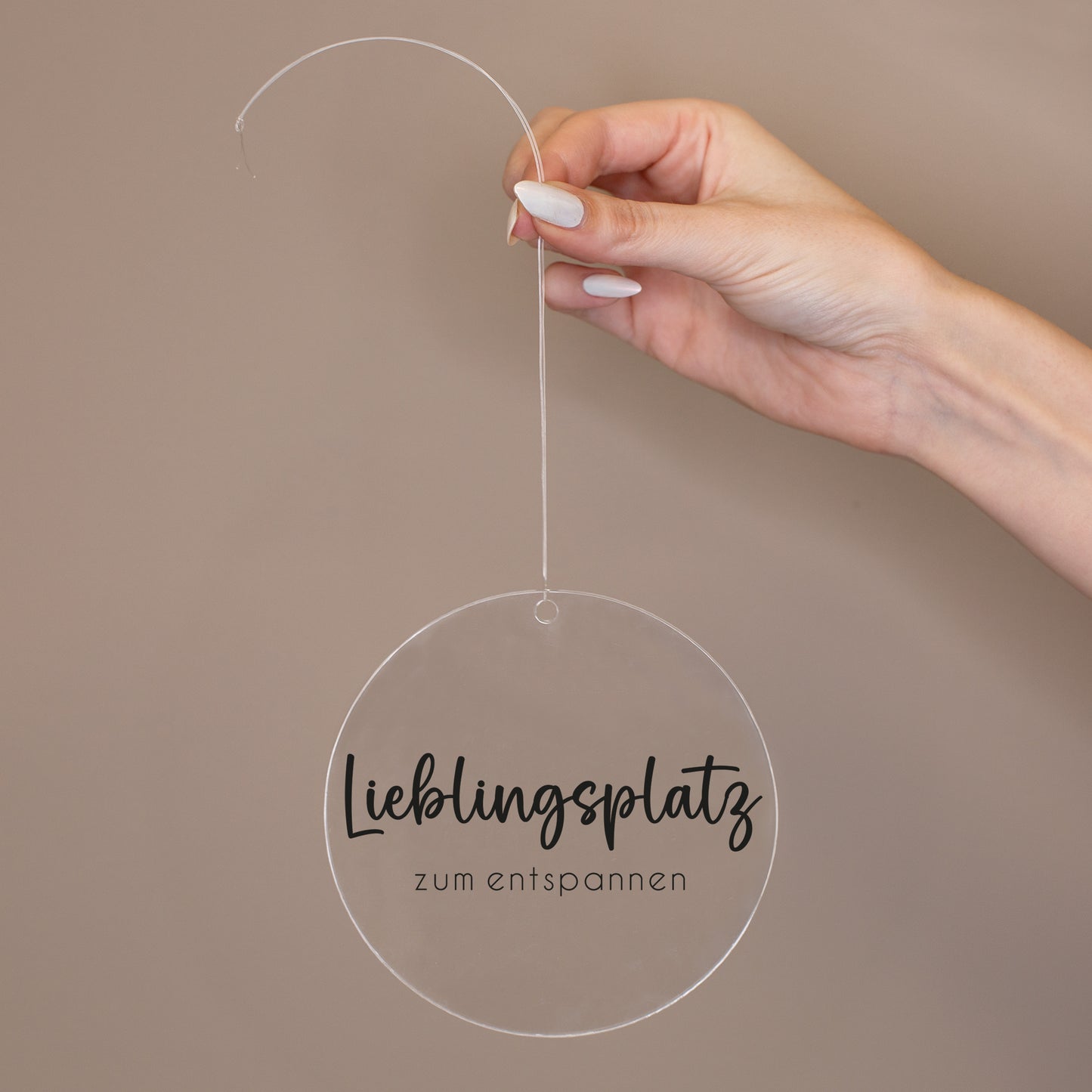 Runder Acrylanhänger Lieblingsplatz zum entspannen wird an transparentem Band in der Hand gehalten