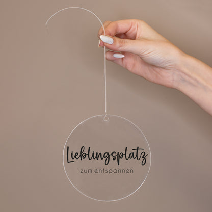 Runder Acrylanhänger Lieblingsplatz zum entspannen wird an transparentem Band in der Hand gehalten