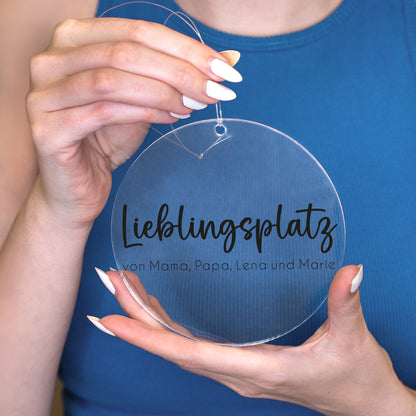 Personalisierter Acrylanhänger Lieblingsplatz von Mama Papa Lena und Marie wird vor blauem Oberteil in den Händen gehalten