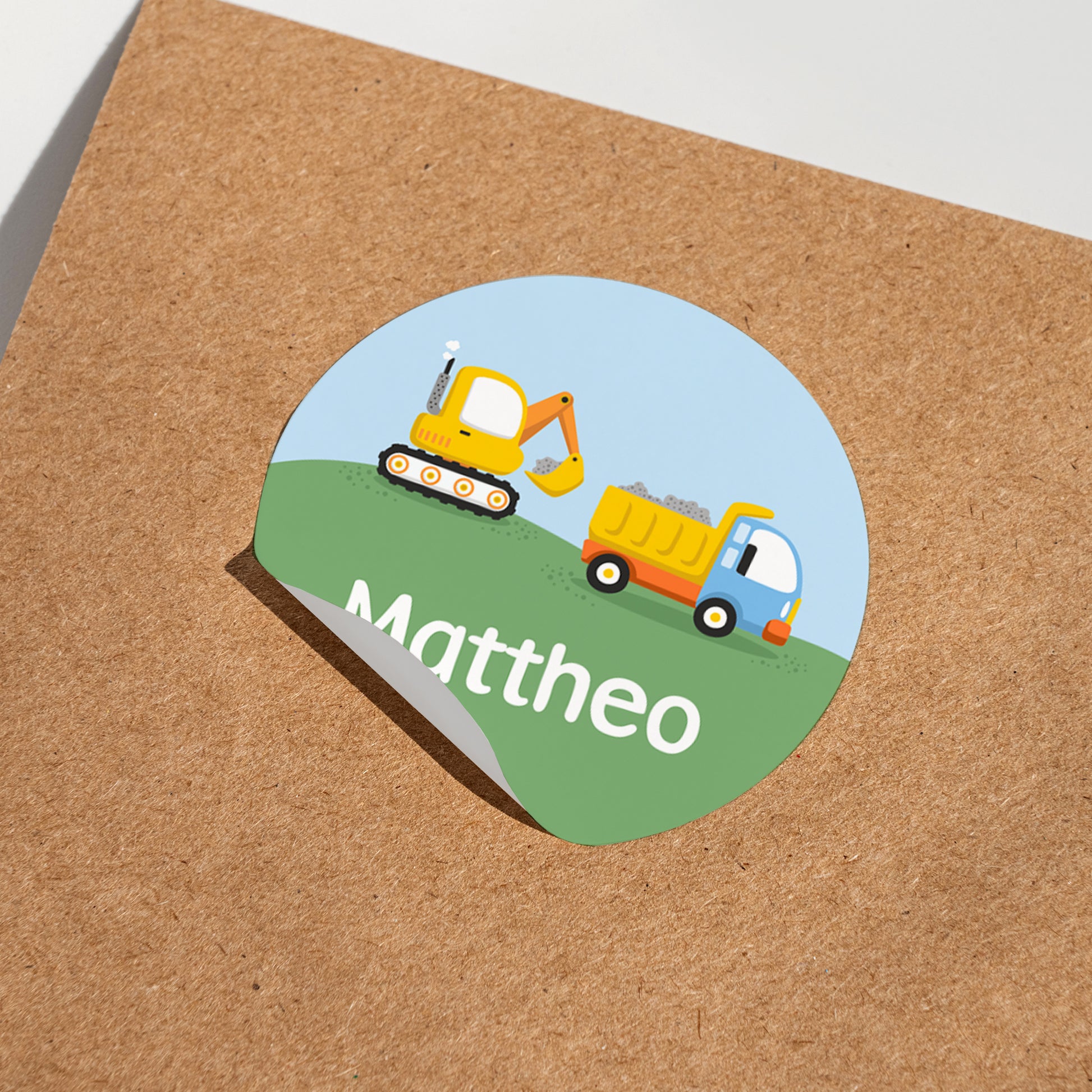 Runder Namensaufkleber mit Bagger und Kipplaster sowie Name Mattheo auf Karton