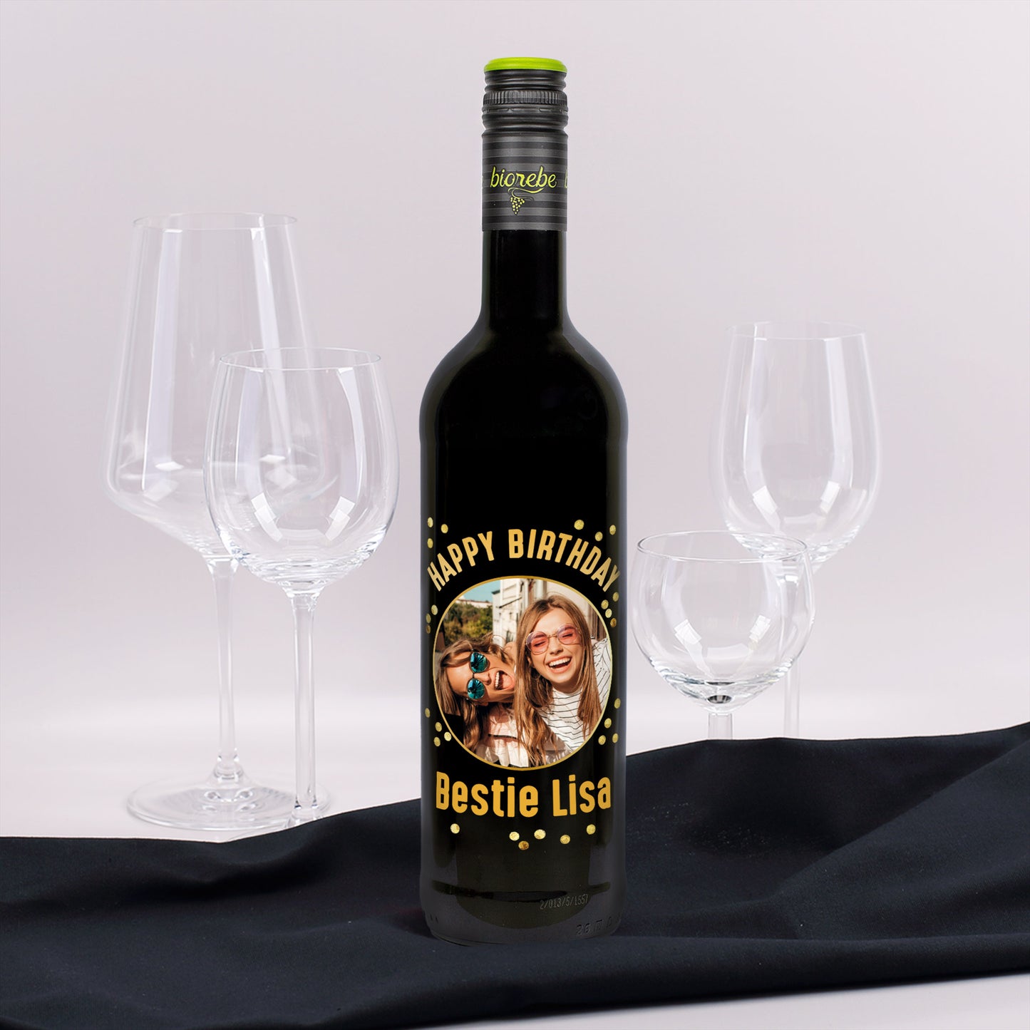 Weinflasche mit personalisiertem Etikett „Happy Birthday Bestie Lisa“ und Foto von zwei lachenden Frauen, umgeben von Weingläsern.