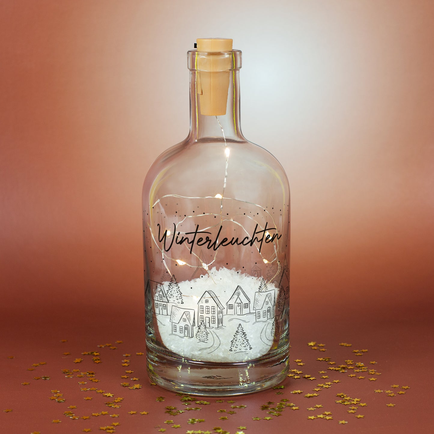 Personalisierbare Glasflasche mit LED-Lichterkette und Winterlandschaft, gefüllt mit Kunstschnee als Weihnachtsdeko.