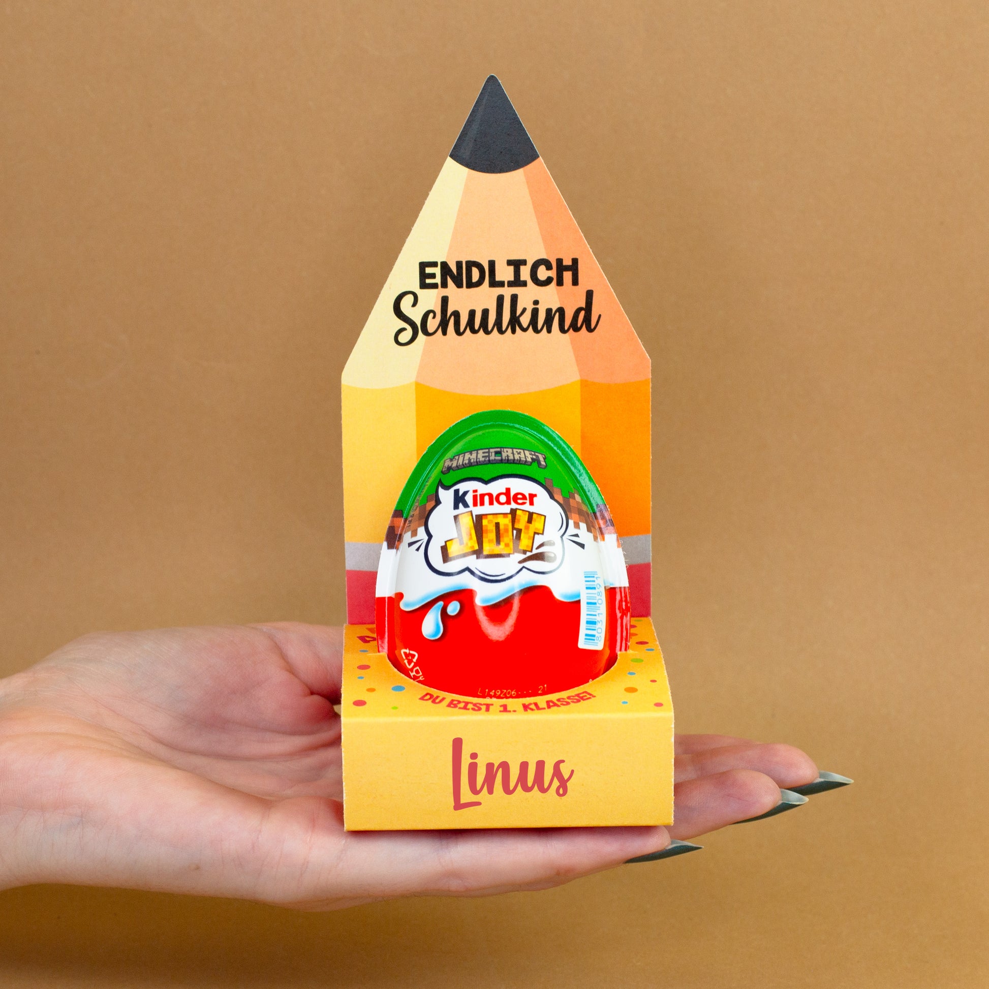 Einschulungsgeschenk mit Kinder Joy und personalisierter Verpackung mit Name Linus in einer Hand