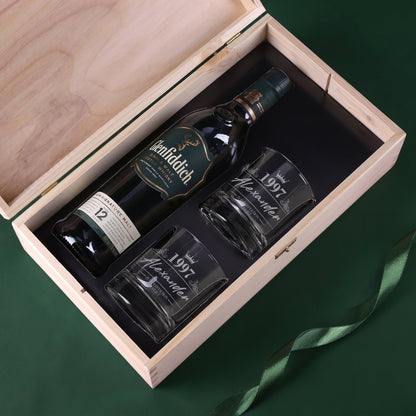 Offene Holzkiste mit Glenfiddich Whiskyflasche und zwei gravierten Whiskygläsern im schwarzen Inlay