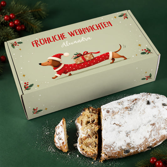 Personalisierte Stollen Geschenkbox mit Dackel in Weihnachtskleidung neben angeschnittenem Rosinenstollen
