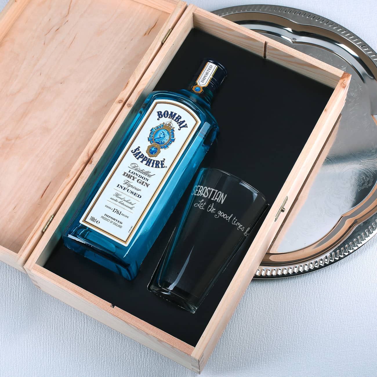 Bombay Sapphire Gin und graviertes Glas liegen sicher im Inneren der Holzkiste