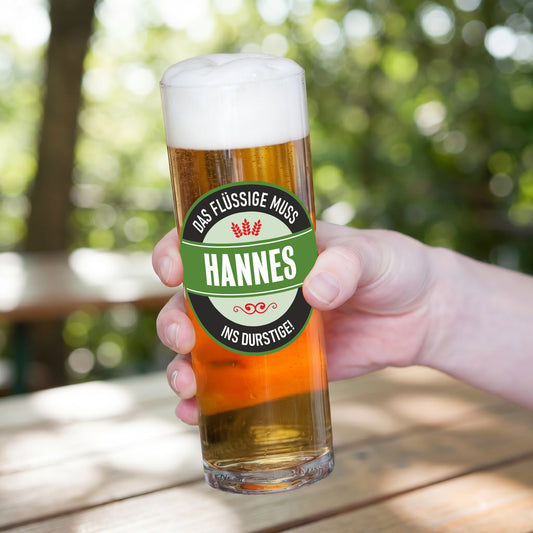 Kölschglas mit Wunschtext Das Flüssige muss ins Durstige und Name Hannes in der Hand
