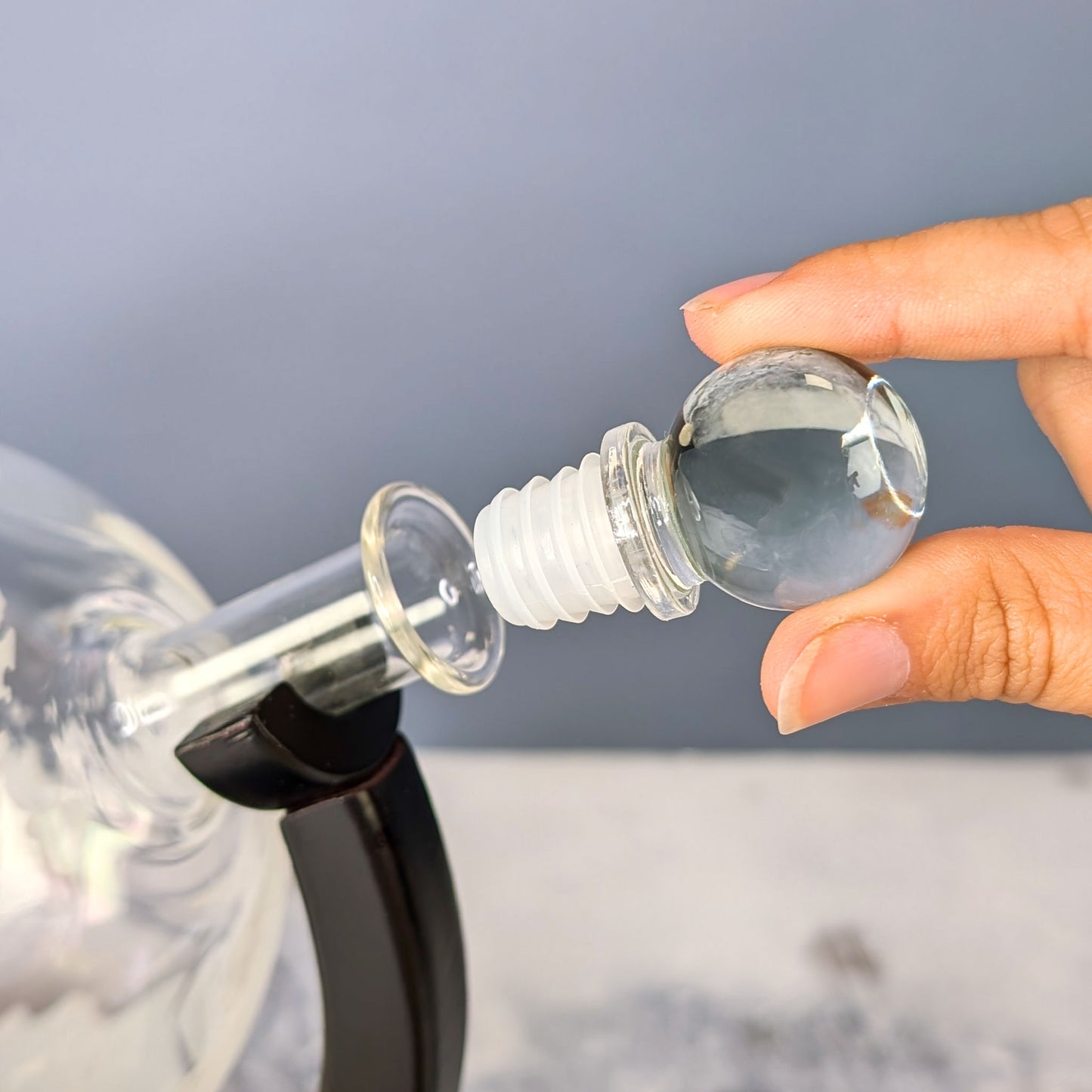 Glas-Aromaverschluss mit Dichtung wird in den Flaschenhals des Dekanters eingesetzt – Hand hält Verschluss