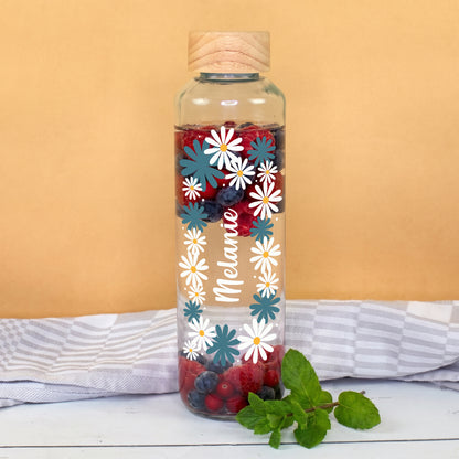 Personalisierte Trinkflasche aus Glas mit Blumenmotiv und Name Melanie, gefüllt mit Wasser, Beeren und Minze