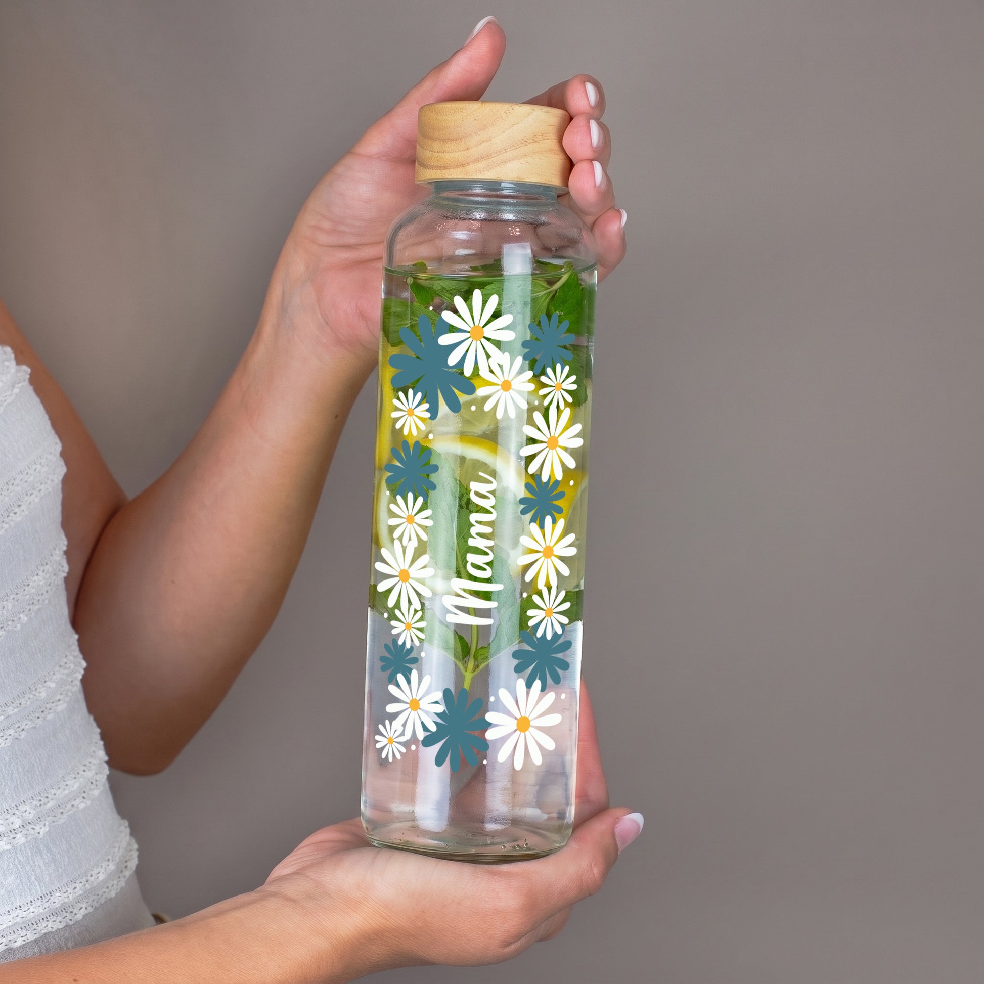 Personalisierte 600 ml Trinkflasche aus recyceltem Glas mit Name Mama und floralem Motiv in der Hand