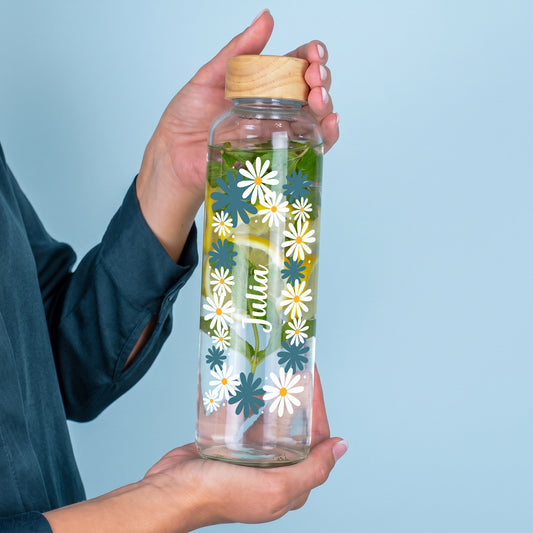 Personalisierte 600 ml Trinkflasche aus recyceltem Glas mit Wunschnamen und floralem Motiv in der Hand