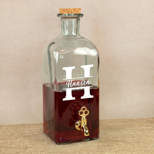 Personalisierter Glas Getränkespender mit Zapfhahn, Initiale und Name, gefüllt mit rotem Getränk auf Leinenuntergrund