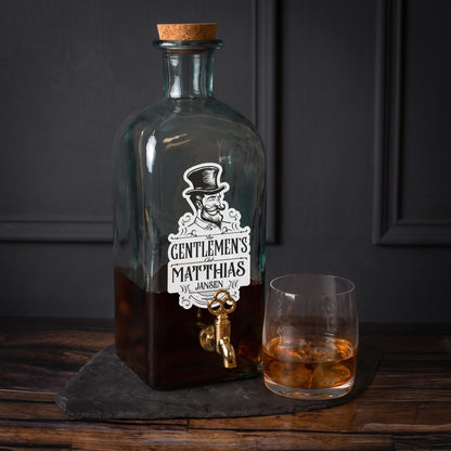 Personalisierter Glas Getränkespender The Gentlemens Club mit Whiskyglas und Zapfhahn auf dunklem Untergrund