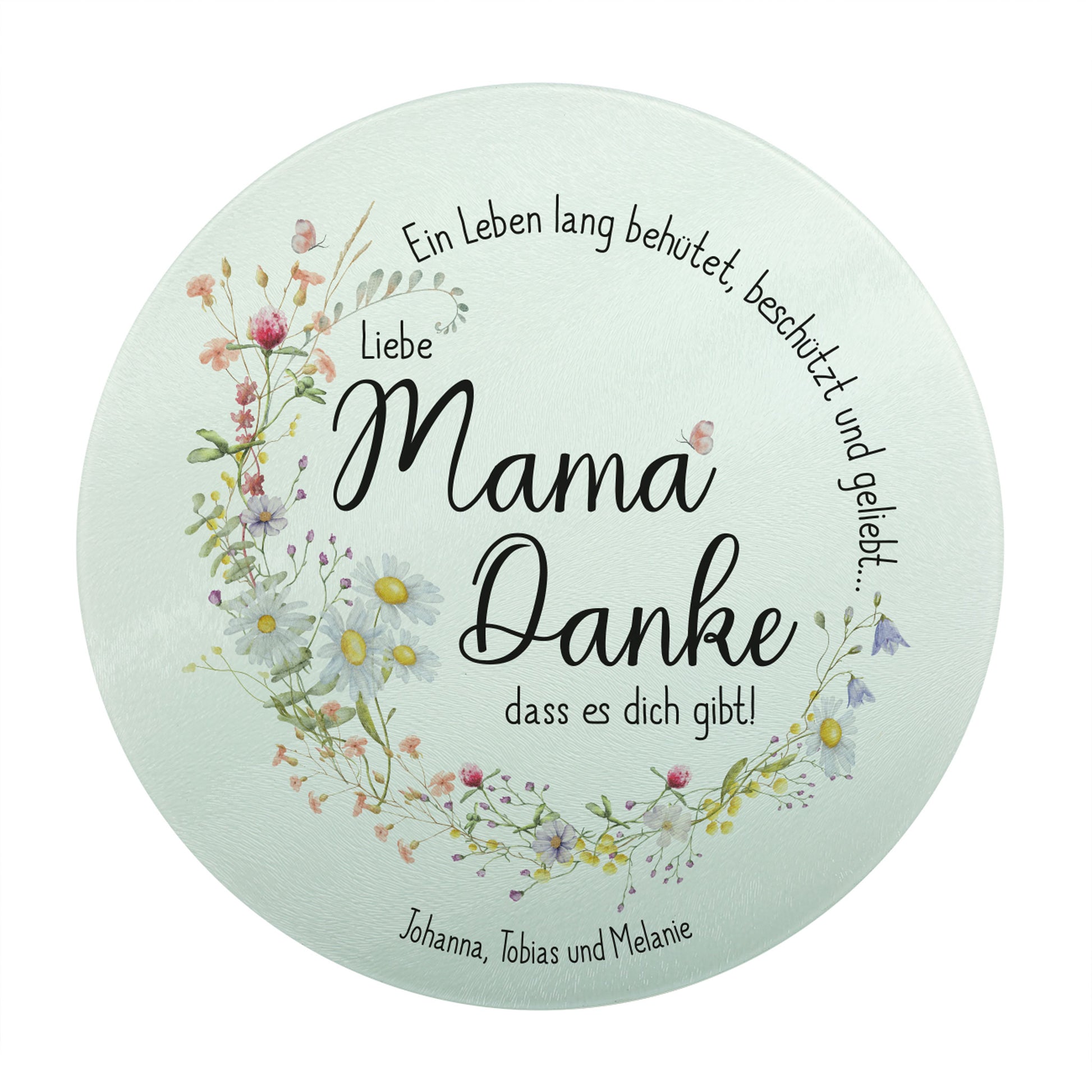 Produktbild des runden Glasbrettchens mit dem Spruch „Ein Leben lang behütet, beschützt und geliebt…“. Der Schriftzug und der zarte Wiesenblumen-Kranz bilden gemeinsam einen harmonischen Kreis. In der Mitte steht „Liebe Mama, Danke, dass es dich gibt!“. Die untere personalisierte Textzeile lautet „Johanna, Tobias und Melanie“.