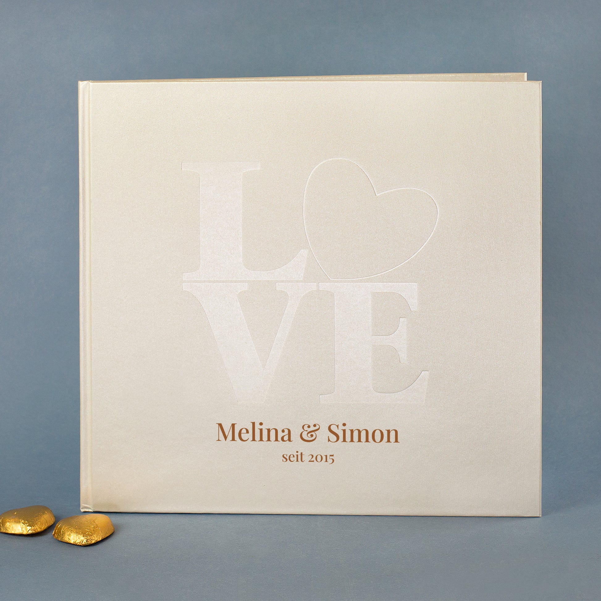 Personalisierbares Gästebuch Hochzeit cremeweiß mit LOVE-Prägung und Herz, Beispielnamen Lisa & Jakob