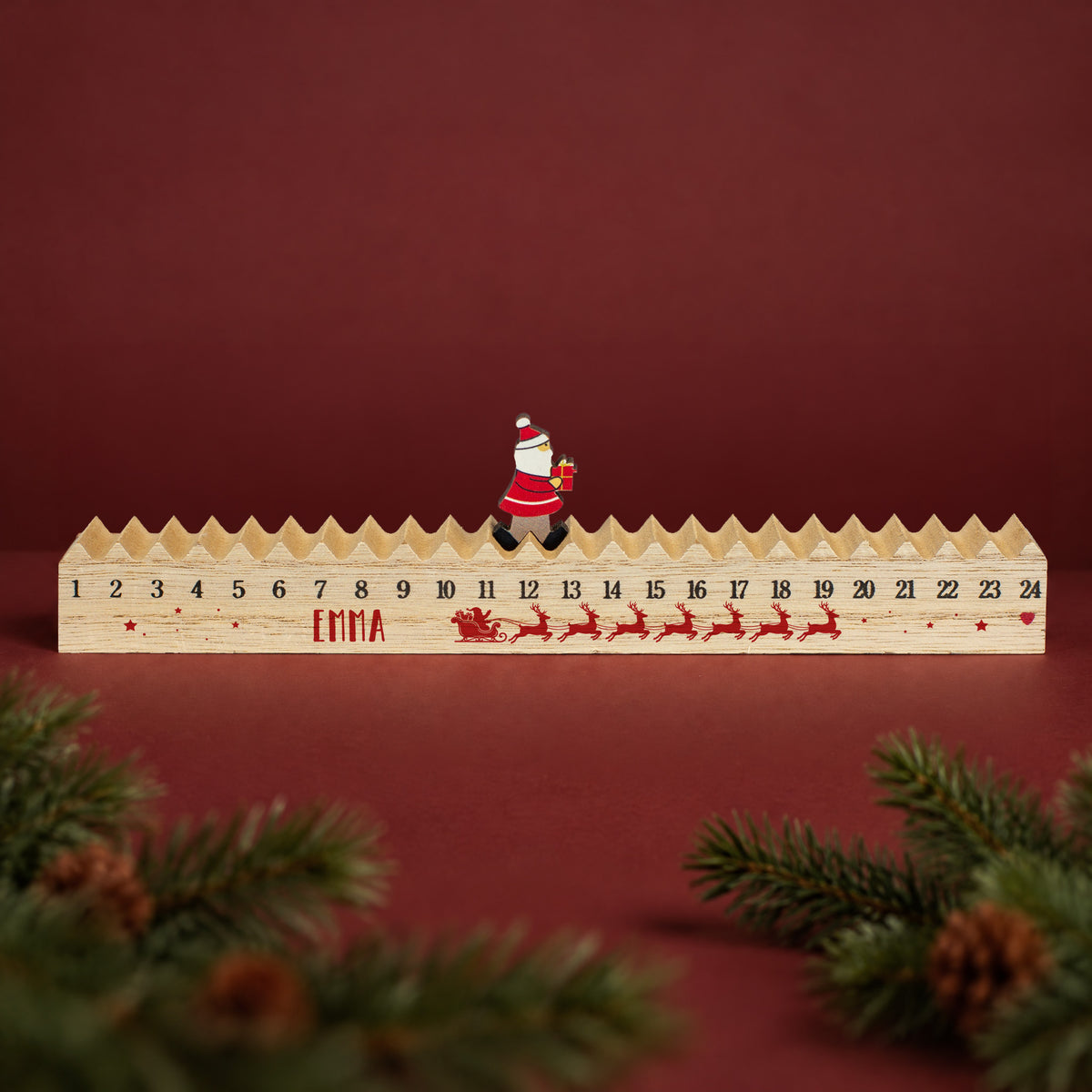 Personalisierter Holz-Adventskalender mit Wunschnamen, Zahlen 1 bis 24 und beweglichem Weihnachtsmann auf der oberen Kalenderleiste