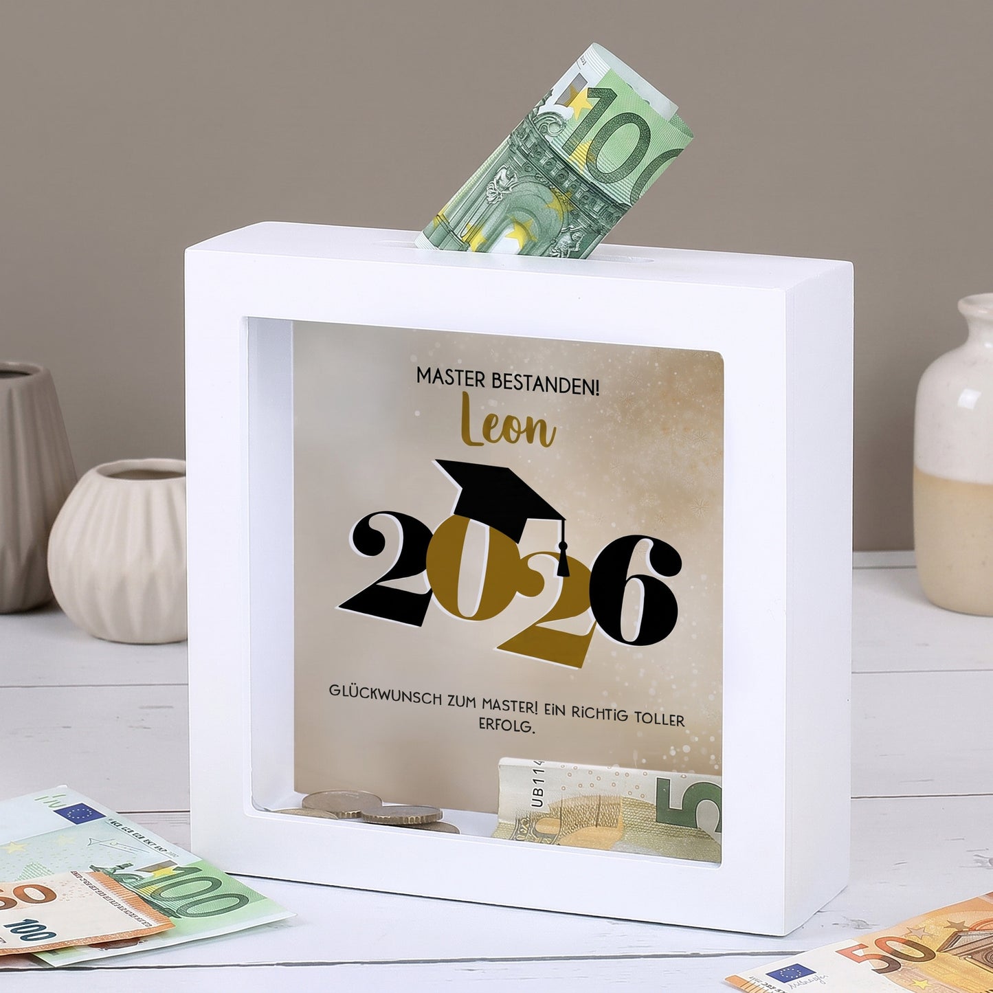 Personalisierte Spardose Master bestanden 2026 mit Name Leon, Geldschein und Münzen im Rahmen